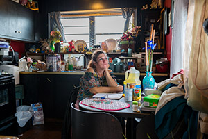 A photo of a woman, photographed as part of The Debt Project, sitting at a kitchen table